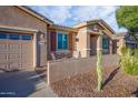 Front view of a tan house with a two-car garage and seating area at 42531 W Heavenly Pl, Maricopa, AZ 85138