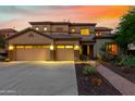 Two-story home with three-car garage and desert landscaping, illuminated at dusk at 5027 W El Cortez Trl, Phoenix, AZ 85083