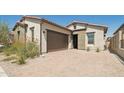 Tan two-car garage home with a landscaped yard and brick driveway at 38500 N School House Rd # 5, Cave Creek, AZ 85331