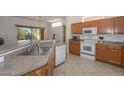 Kitchen with wood cabinets, stainless steel sink and white appliances at 15574 W Vista Grande Ln, Surprise, AZ 85374