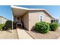 Front view of tan mobile home with walkway and landscaping at 11596 W Sierra Dawn Blvd # 36, Surprise, AZ 85378