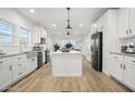 Modern kitchen with white cabinets, a large island, and stainless steel appliances at 8082 W Jadan St, Coolidge, AZ 85128