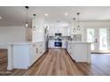 Modern white kitchen with island, stainless steel appliances, and light wood floors at 9901 W Raintree Dr, Sun City, AZ 85351