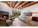 Cozy bedroom with fireplace, wood beam ceiling, and patio access at 6711 E Camelback Rd # 3, Scottsdale, AZ 85251