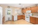 Kitchen with wood cabinets, white appliances, and tile floor at 15924 W Elm St, Surprise, AZ 85374