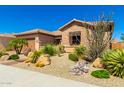 House exterior featuring stone accents, desert landscaping, and a two-car garage at 26446 W Lone Cactus Dr, Buckeye, AZ 85396