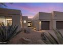 Desert landscaping surrounds this modern home's stucco exterior, entryway, and two-car garage at 7056 E Mighty Saguaro Way, Scottsdale, AZ 85266