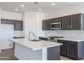 Modern kitchen featuring dark cabinetry, white quartz countertops, and tile backsplash at 25214 N 172Nd Ln, Surprise, AZ 85387