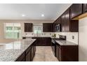 Modern kitchen with granite countertops and dark wood cabinets at 37784 W San Sisto Ave, Maricopa, AZ 85138