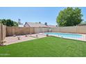 Landscaped backyard oasis with a sparkling pool and artificial turf at 7621 W Comet Ave, Peoria, AZ 85345