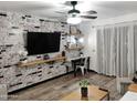 Living room with a brick accent wall, a large TV, and a small workspace at 3119 W Cochise Dr # 225, Phoenix, AZ 85051