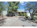 Ranch style home with mature trees and gravel driveway at 1140 Jediondia Dr, Wickenburg, AZ 85390