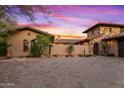 Elegant home exterior at sunset with stone and stucco at 36975 N Mirabel Club Dr, Scottsdale, AZ 85262