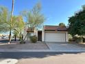Tan colored stucco home with a white garage door and mature landscaping at 7006 E Jensen St # 83, Mesa, AZ 85207