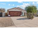 Single-story home with wood garage door, red front door, and desert landscaping at 16275 W Buchanan St, Goodyear, AZ 85338