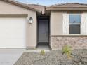 Front entry of single story home with stone accents and a two-car garage at 16032 W Hackamore Dr, Surprise, AZ 85387