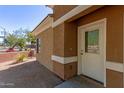 Exterior view of a light brown stucco building with a white door and landscaping at 854 S San Marcos Dr Bldg 1 Dr # A, Apache Junction, AZ 85120