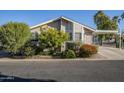 Tan mobile home with carport, landscaping, and street view at 8865 E Baseline Rd # 1822, Mesa, AZ 85209