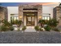 Modern home exterior with a stone and wood facade, and a paved driveway at 24351 N 97Th Dr, Peoria, AZ 85383
