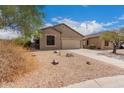 Tan house with two-car garage and desert landscaping at 6599 E Casa De Leon Ln, Gold Canyon, AZ 85118