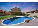 Inviting kidney-shaped pool with grassy backyard and mountain views at 18516 W Sweet Acacia Dr, Goodyear, AZ 85338