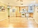 Kitchen with light wood cabinets, white appliances and laminate wood floors at 9427 E University Dr # 100, Mesa, AZ 85207
