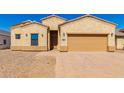 Tan stucco home with a two-car garage and landscaped yard at 9290 W Troy Dr, Arizona City, AZ 85123