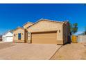 One-story house with tan exterior, two-car garage, and paved driveway at 9290 W Troy Dr, Arizona City, AZ 85123