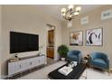 Living room with a modern TV stand and two teal armchairs at 42929 W Castle Cove Cir, Maricopa, AZ 85138