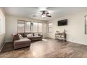 Living room with L-shaped sofa, hardwood floors, and large windows at 16079 W Williams St, Goodyear, AZ 85338