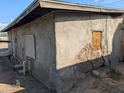 Side of house with damaged stucco and boarded window at 208 W Dr Martin Luther King Jr St, Eloy, AZ 85131