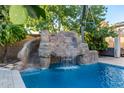 Resort-style backyard oasis with a waterfall and rock features at 20475 E Palomino Dr, Queen Creek, AZ 85142