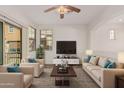 Spacious living room with beige sofas, a large TV, and a ceiling fan at 7772 W Pipestone Pl, Phoenix, AZ 85035