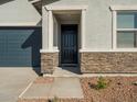 Front entrance with stone accents and dark wooden door at 17402 W Sanna St, Waddell, AZ 85355