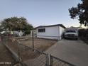 Mobile home with covered porch, driveway and partial fence at 9017 E Butternut Ave, Mesa, AZ 85208