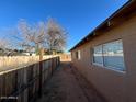 Side yard with dirt ground, wooden fence, and a tree at 3542 E Earll Dr, Phoenix, AZ 85018