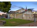 Two-story house with three-car garage and manicured lawn at dusk at 7752 W Mary Jane Ln, Peoria, AZ 85382
