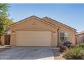 Tan house with a two-car garage and well-maintained landscaping at 17143 W Port Royale Ln, Surprise, AZ 85388