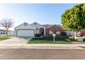 House exterior featuring a brick facade, two-car garage, and neatly kept lawn at 15274 N 63Rd Ln, Glendale, AZ 85306