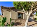 Tan house exterior with stone accents and mature trees in the front yard at 13506 W Earll Dr, Avondale, AZ 85392