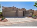 Tan two-story house with a three-car garage and desert landscaping at 42915 W Kingfisher Dr, Maricopa, AZ 85138