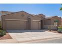 Tan two-story house with a three-car garage and desert landscaping at 42915 W Kingfisher Dr, Maricopa, AZ 85138