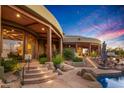 Luxury home's backyard featuring a pool and stone patio at sunset at 40523 N 102Nd Pl, Scottsdale, AZ 85262