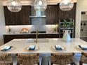 Modern kitchen with dark cabinetry, quartz countertops, and a large island at 9963 W Cora Ln, Avondale, AZ 85392