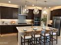 Spacious kitchen featuring dark wood cabinets and a large island with seating at 9963 W Cora Ln, Avondale, AZ 85392