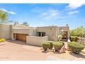 Front view of a tan stucco home with a wooden door and desert landscaping at 10044 E Graythorn Dr, Scottsdale, AZ 85262