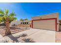 House exterior with a beige stucco finish, red accents, and a two-car garage at 10014 N 66Th Ln, Glendale, AZ 85302