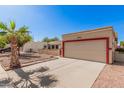 House exterior with a beige stucco finish, red accents, and a two-car garage at 10014 N 66Th Ln, Glendale, AZ 85302