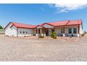 Single story home with red metal roof, covered porch, and gravel driveway at 5604 S 225Th Ave, Buckeye, AZ 85326
