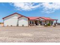 Single story home with red metal roof, covered porch, and gravel driveway at 5604 S 225Th Ave, Buckeye, AZ 85326